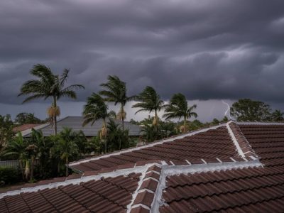 Modern Brisbane home with a solid, freshly repointed tiled roof standing strong against approaching dark storm clouds, symbolizing storm season readiness.