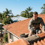 A roofer applies flexible pointing to a tiled roof in Brisbane on a bright winter day.